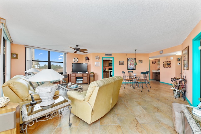 living room with ceiling fan and a textured ceiling