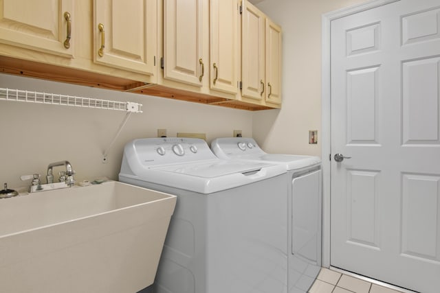 laundry area featuring washer and clothes dryer, sink, light tile patterned flooring, and cabinets