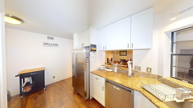 kitchen featuring white cabinets, stainless steel appliances, light stone counters, and dark hardwood / wood-style floors