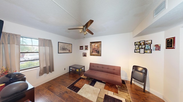 living room with dark hardwood / wood-style floors, ceiling fan, and a textured ceiling