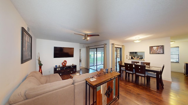 living room featuring a textured ceiling, ceiling fan, and dark hardwood / wood-style floors