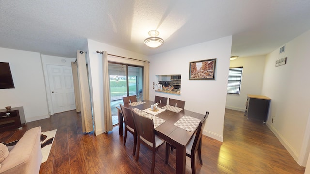 dining area with dark hardwood / wood-style flooring and a textured ceiling