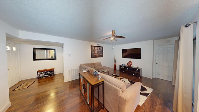 living room featuring a textured ceiling, ceiling fan, and dark wood-type flooring