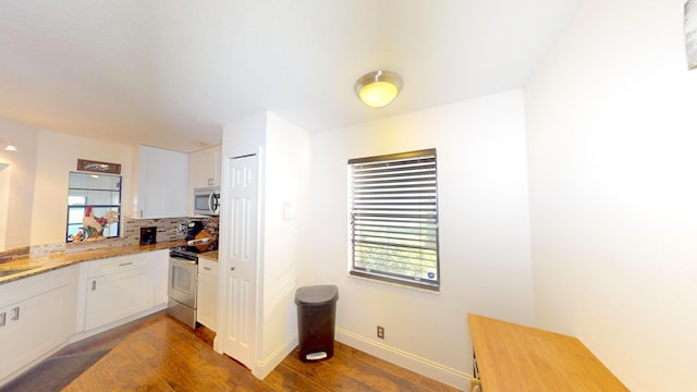 kitchen featuring tasteful backsplash, white cabinetry, dark wood-type flooring, and stainless steel appliances