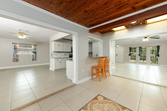 kitchen with light tile patterned flooring, white cabinetry, ceiling fan, and tasteful backsplash