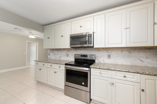 kitchen featuring light tile patterned flooring, appliances with stainless steel finishes, tasteful backsplash, white cabinets, and light stone counters