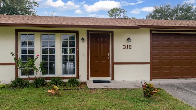 entrance to property with a garage and a lawn