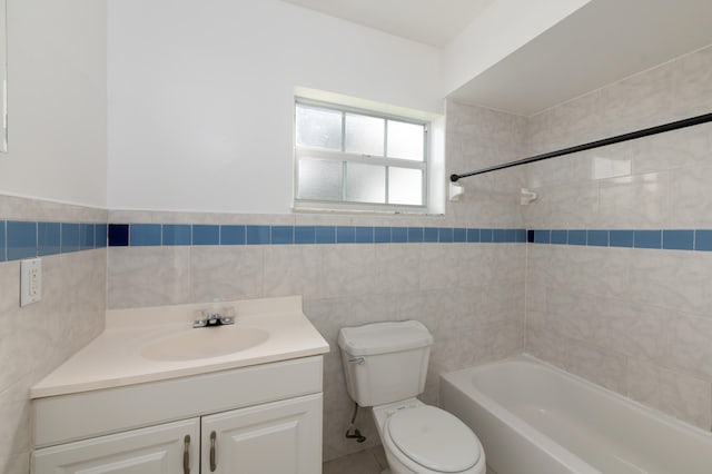 full bathroom featuring tile walls, vanity, tiled shower / bath, and toilet