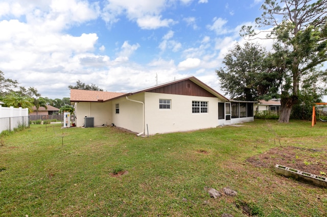 rear view of house with a yard, central AC, and a sunroom