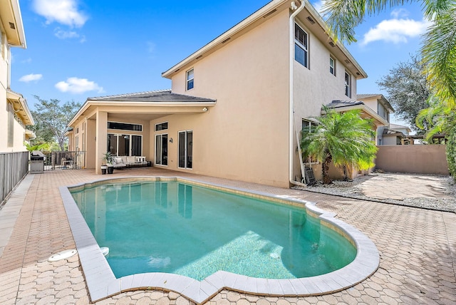 back of property with a fenced in pool, outdoor lounge area, and a patio