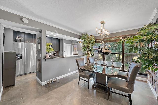 tiled dining room featuring a textured ceiling, an inviting chandelier, crown molding, and sink