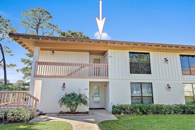 view of front of house featuring a balcony and a front lawn