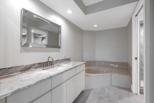 bathroom featuring vanity and tiled bath