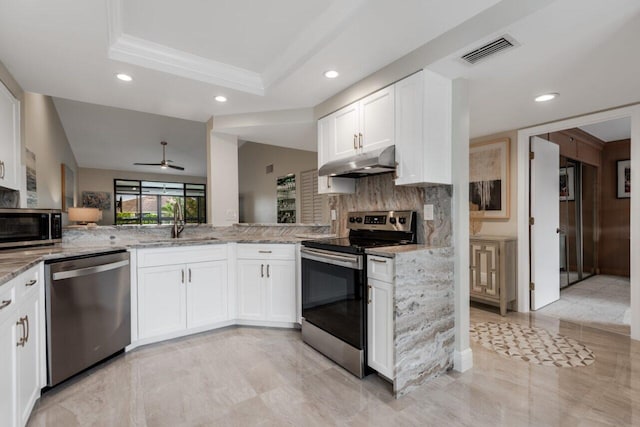 kitchen with backsplash, stainless steel appliances, light stone counters, white cabinets, and a raised ceiling