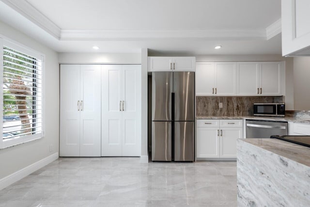 kitchen featuring white cabinetry, light stone counters, appliances with stainless steel finishes, a raised ceiling, and decorative backsplash