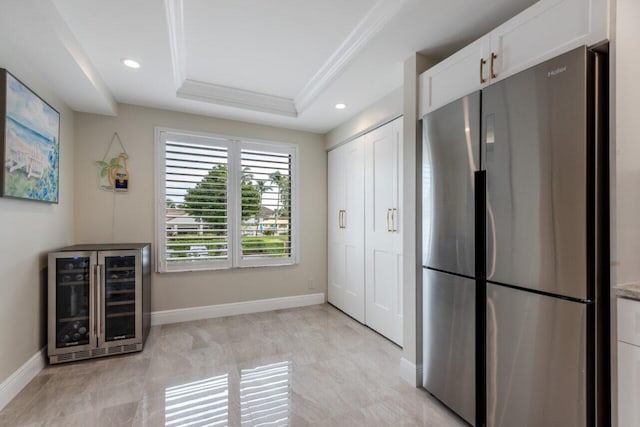 kitchen featuring crown molding, stainless steel fridge, white cabinetry, wine cooler, and a raised ceiling