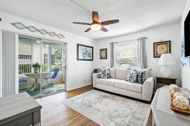 living room with a textured ceiling, light hardwood / wood-style floors, and ceiling fan