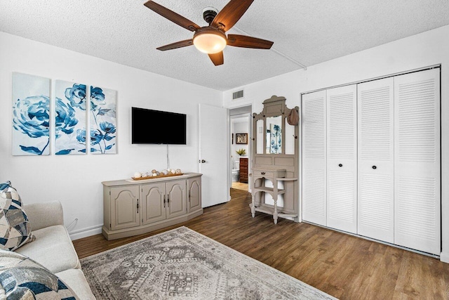 living room with a textured ceiling, ceiling fan, and dark hardwood / wood-style floors