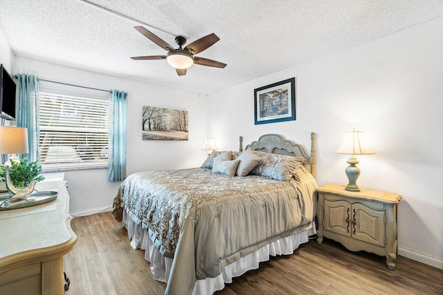 bedroom with ceiling fan, light hardwood / wood-style floors, and a textured ceiling