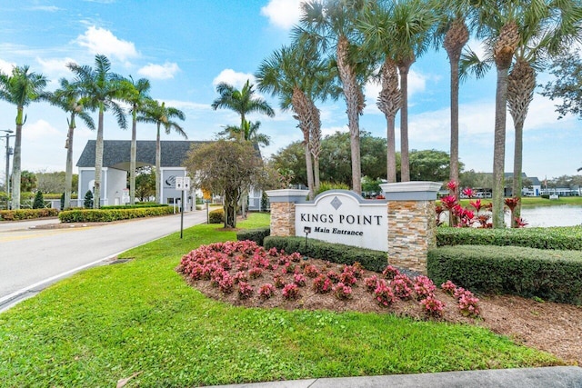 community sign with a water view and a lawn