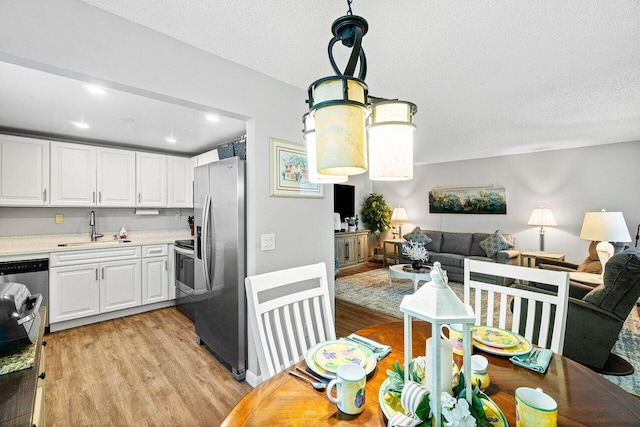 kitchen with white cabinetry, sink, stainless steel appliances, light hardwood / wood-style flooring, and a textured ceiling