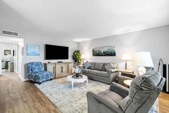 living room with a textured ceiling and light wood-type flooring