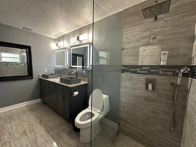 bathroom featuring vanity, a textured ceiling, tiled shower, tile walls, and toilet