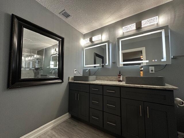 bathroom with hardwood / wood-style flooring, vanity, and a textured ceiling