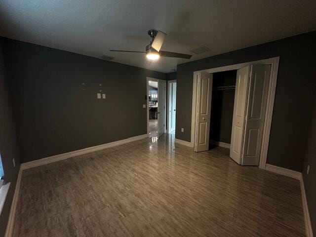 unfurnished bedroom featuring wood-type flooring, a closet, and ceiling fan