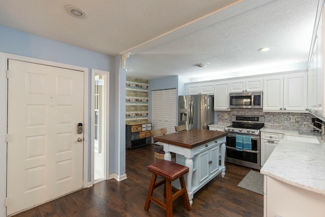 kitchen with butcher block countertops, white cabinets, sink, and stainless steel appliances