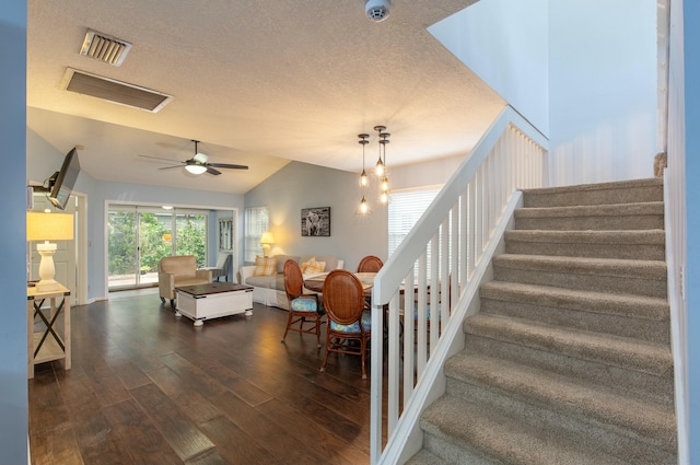 staircase featuring a textured ceiling, hardwood / wood-style floors, ceiling fan with notable chandelier, and lofted ceiling