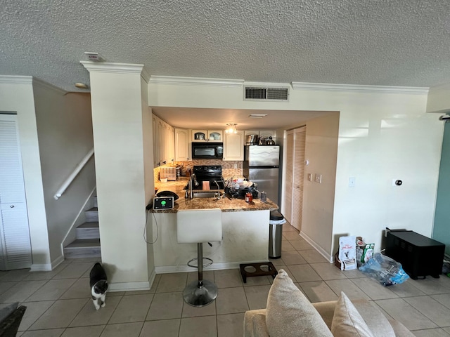 kitchen with kitchen peninsula, light tile patterned floors, ornamental molding, and black appliances