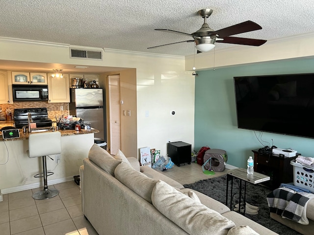 tiled living room with a textured ceiling, ceiling fan, and crown molding