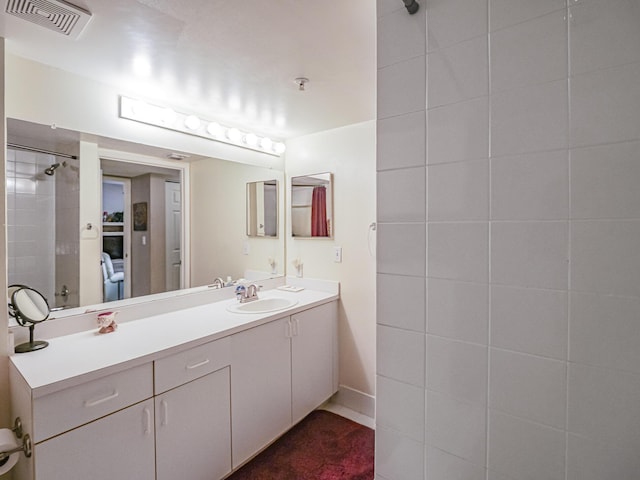 bathroom with visible vents, vanity, and walk in shower