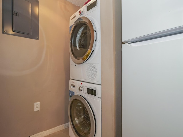 laundry area with baseboards, laundry area, electric panel, and stacked washer / drying machine