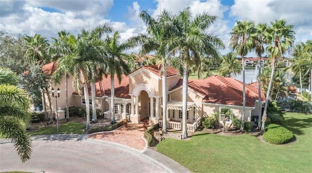 view of front of property with stucco siding, a tile roof, and a front yard