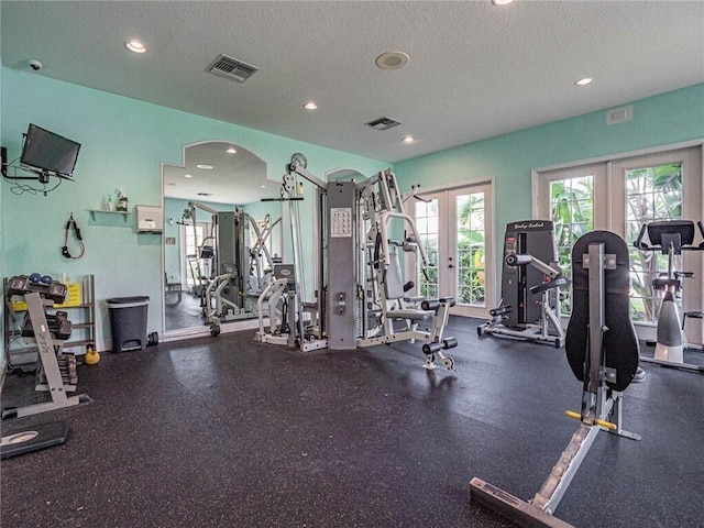 workout area featuring visible vents, arched walkways, a textured ceiling, and french doors