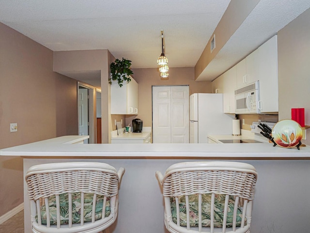 kitchen featuring a peninsula, white appliances, baseboards, white cabinets, and light countertops