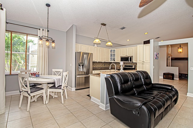 kitchen with decorative light fixtures, light stone counters, backsplash, and appliances with stainless steel finishes