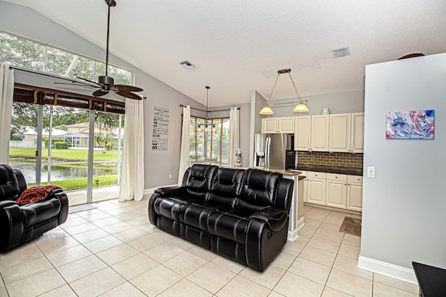 living room featuring a textured ceiling, ceiling fan, light tile patterned floors, and vaulted ceiling