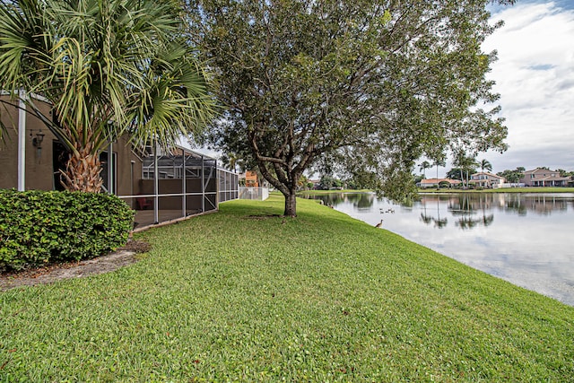 view of yard with a lanai and a water view