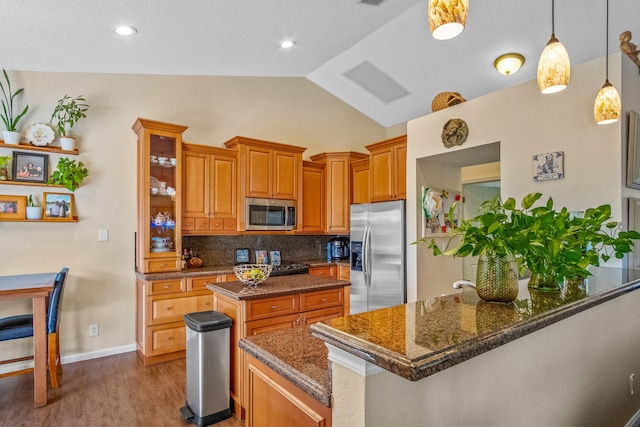 kitchen featuring lofted ceiling, hanging light fixtures, light wood-type flooring, tasteful backsplash, and stainless steel appliances