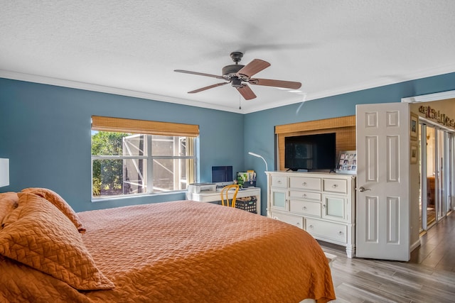 bedroom featuring a textured ceiling, light wood-type flooring, ceiling fan, and ornamental molding