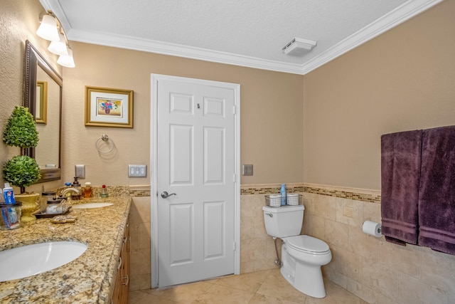 bathroom featuring a textured ceiling, vanity, ornamental molding, and tile walls