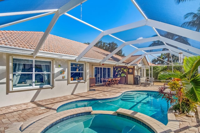 view of swimming pool with an in ground hot tub, a lanai, and a patio area