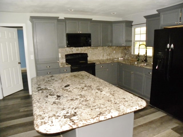 kitchen with black appliances, a center island, sink, and dark wood-type flooring