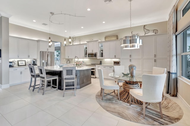 kitchen featuring stainless steel appliances, crown molding, hanging light fixtures, and a spacious island