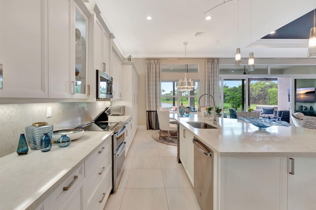 kitchen with sink, decorative light fixtures, a kitchen island with sink, white cabinets, and appliances with stainless steel finishes