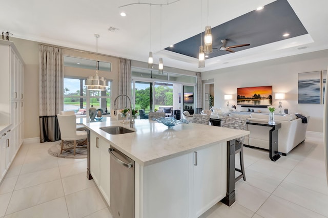 kitchen with white cabinets, a kitchen island with sink, hanging light fixtures, and a tray ceiling