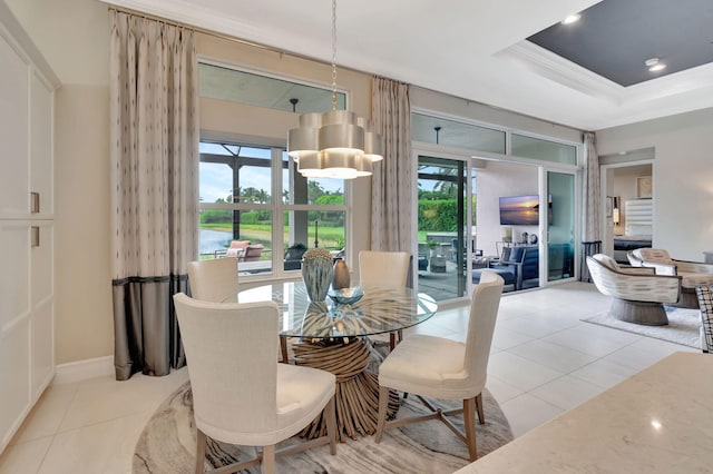 tiled dining area with a tray ceiling and ornamental molding